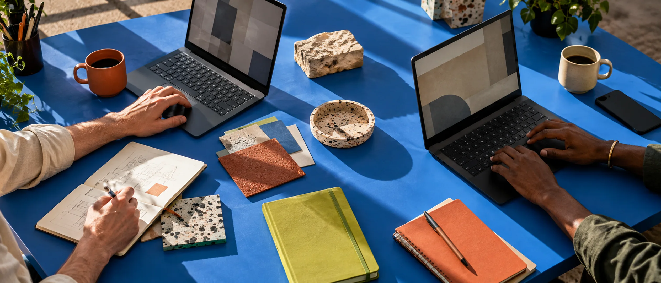Hands, laptops, notebooks and coffee on a blue planning table
