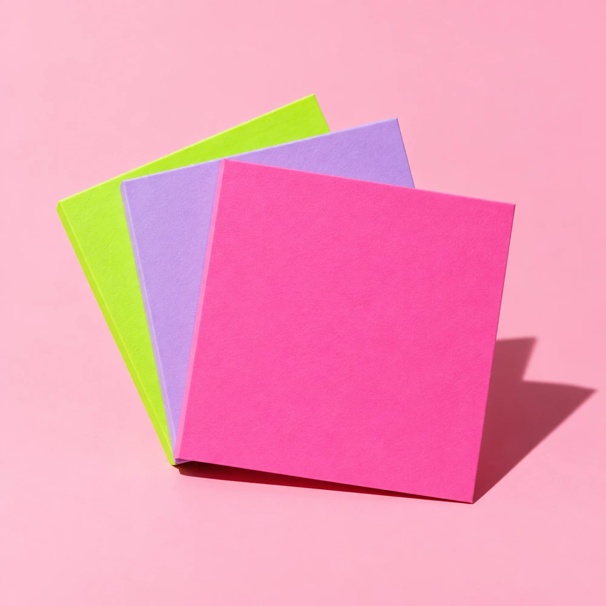 Blank pink, lime and lilac cards fanned out on a pink backdrop