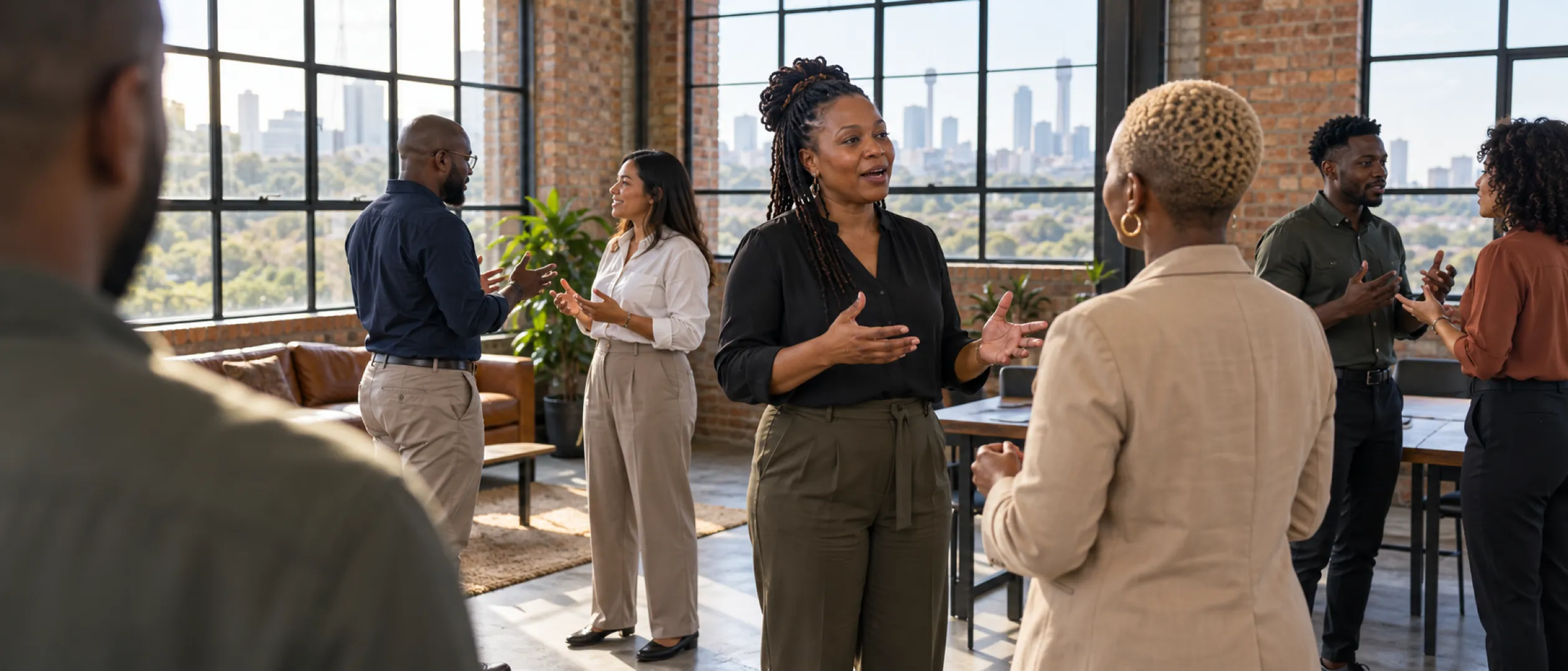 A facilitator leading an in-person workshop in a brick-walled training room above the city